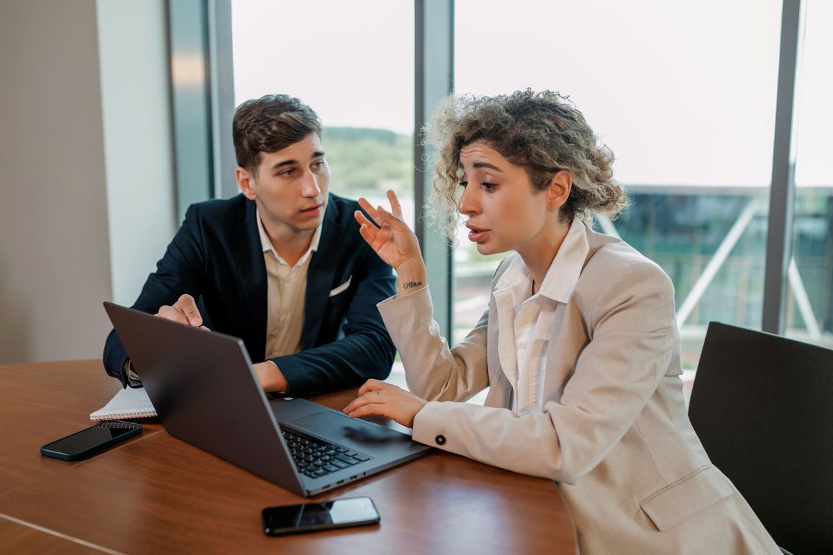 Coworkers comparing notes at a desk